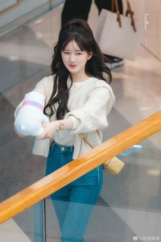 a woman holding a stuffed animal in her hand while walking down an escalator