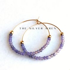 Tanzanite Gold Hoop Earrings D E T A I L S These gorgeous hoop earrings are created with Genuine Natural Tanzanite 3mm beads and 14kt gold filled accents   Beaded by hand  14kt gold filled 35mm hoops  ∙ EXTRA LOVE ∙ Crafted and curated just for you in the desert of our Arizona studio. All of our jewelry comes gift packaged!  We are happy to leave a note if this is a special gift, just let us know in the message box at checkout.  PRODUCTION ∙ TIMES All items are made to order. Please check the to Faceted Hoop Earrings As Gift, Purple Hoop Earrings As Gift, Faceted Hoop Jewelry For Gifts, Jewelry Hoop Earrings, Earrings Gold Hoop, Tanzanite Jewelry, Tanzanite Earrings, Gift Best Friend, Hoop Earrings Gold