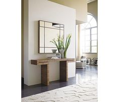 a large mirror sitting on top of a white wall next to a wooden table with a plant in it