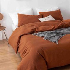 a bed with an orange comforter and pillows