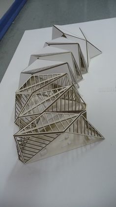 several metal structures sitting on top of a white table next to each other, all in different shapes and sizes