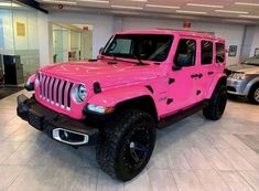 a pink jeep is parked in a showroom