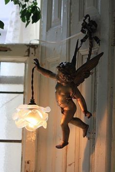 an angel statue hanging from the side of a building next to a light fixture on a door