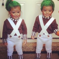 two young children dressed in costumes with green hair and suspenders, standing next to each other