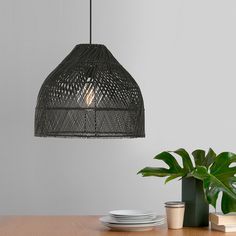 a table topped with plates and a plant next to a light hanging from the ceiling