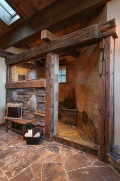 a room with stone floors and wooden beams on the ceiling, along with a fireplace