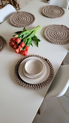 a white table topped with plates and flowers on top of each other next to a vase filled with tulips