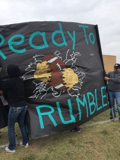 people holding up a sign that says ready to rumble on the side of a field