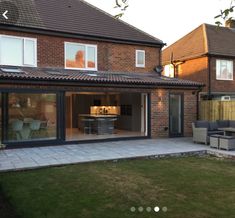 a house with an open patio and dining area in the back yard, surrounded by grass