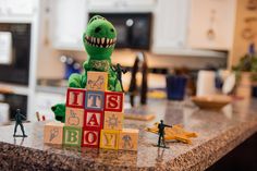 a toy dinosaur with blocks spelling its name it's a boy on the kitchen counter