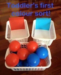 two plastic baskets filled with balloons on top of a wooden floor next to a sign that says toddler's first color sort