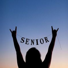 the silhouette of a woman with her hands up in the air holding a sign that says senior