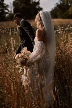 a bride and groom walking through tall grass