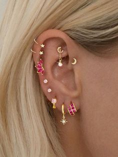 a woman's ear with three different colored stars and moon piercings on it