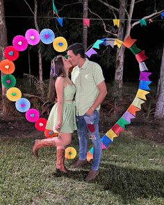 a man and woman standing next to each other in front of a colorful paper circle