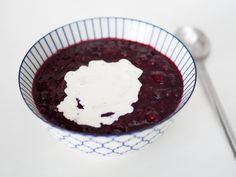 a blue and white bowl filled with food on top of a table next to a spoon