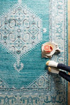 a person cutting up an orange on top of a rug