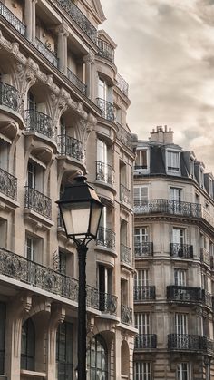 an old fashioned street light in front of a building with balconies on it