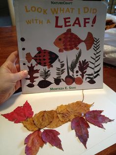 someone is holding up a book with leaves on it and an image of fish in the background