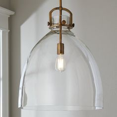 a clear glass light fixture hanging from a ceiling in a room with white walls and windows