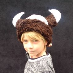 a young boy wearing a brown hat with horns on it's head and ears