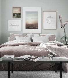 a bedroom with grey walls and pictures on the wall above the bed, along with a coffee table