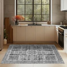 a kitchen with an area rug in front of the stove and sink that is next to a window