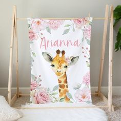 a giraffe with flowers and name on it is sitting in front of a white rug