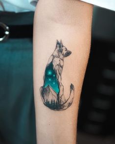 a person with a tattoo on their arm that has a dog and mountains in the background