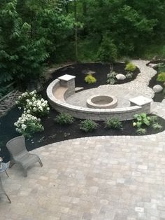 an outdoor patio with seating and fire pit surrounded by greenery, shrubs and trees