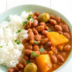 a bowl filled with beans and rice on top of a white table next to a fork