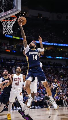 a basketball player jumping up to dunk the ball in front of two other players