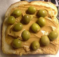 a piece of bread with olives on it and peanut butter spread over the top