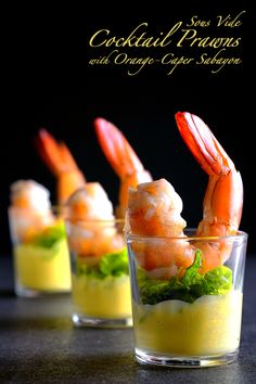 three glasses filled with shrimp and garnish on top of a table