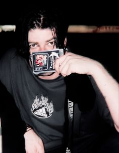 a man taking a photo with his cell phone in front of him, wearing a black t - shirt