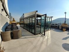 an outdoor patio with chairs and tables next to a building that has glass doors on it