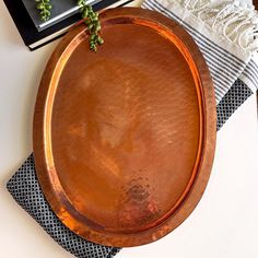 a large copper plate sitting on top of a table next to a black and white towel