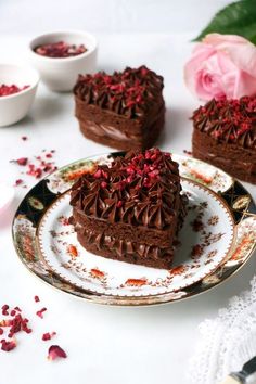 two pieces of chocolate cake sitting on top of a white plate next to pink roses