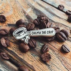 a coffee spoon with the word crema the crop on it surrounded by coffee beans