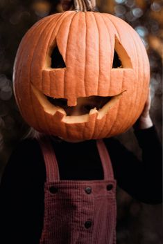 a person holding up a carved pumpkin