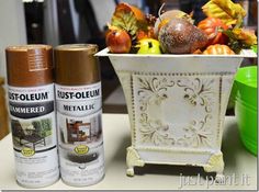 two spray cans sitting on top of a table next to a vase filled with fruit