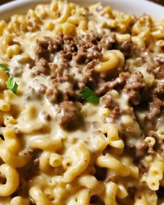 a white bowl filled with macaroni and cheese covered in ground beef, parsley