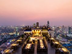 an outdoor dining area overlooking the city at night with lights on and tables set up for dinner