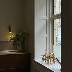 a room with a window and some candles on the table in front of it,