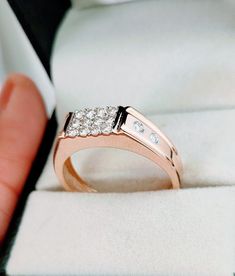 a hand holding a ring with three diamonds on it in a white velvet box that is open to show the inside