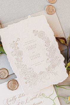 the wedding stationery is laid out on top of an envelope with two coins next to it