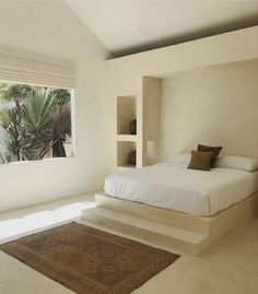 a bed sitting in the middle of a bedroom next to a window with palm trees