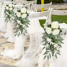 rows of white chairs decorated with flowers and greenery