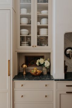 a kitchen with white cabinets and marble counter tops, gold pulls on the cupboards