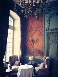 a room with two chairs, a table and a chandelier